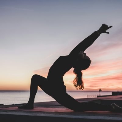 Woman practicing yoga in a peaceful setting, representing the connection between yoga, meditation, and radiant, healthy skin.