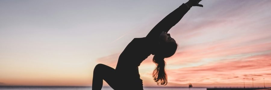 Woman practicing yoga in a peaceful setting, representing the connection between yoga, meditation, and radiant, healthy skin.